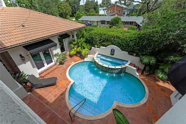 view of swimming pool with an in ground hot tub, pool water feature, a patio area, and french doors