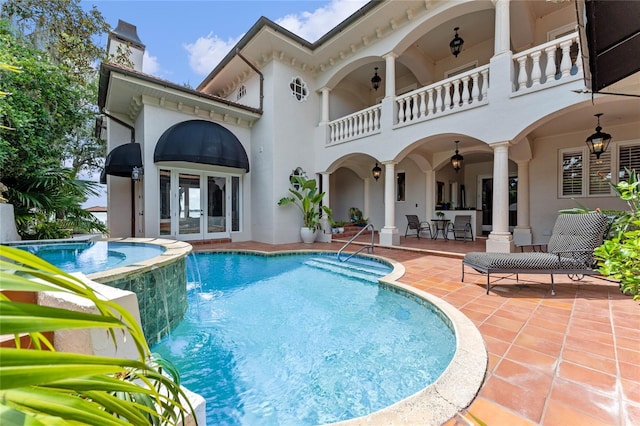 view of pool with a patio, pool water feature, and french doors