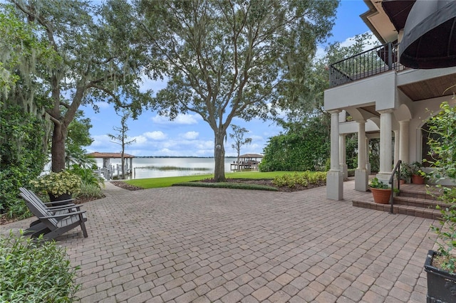 view of patio with a balcony, a water view, and a gazebo