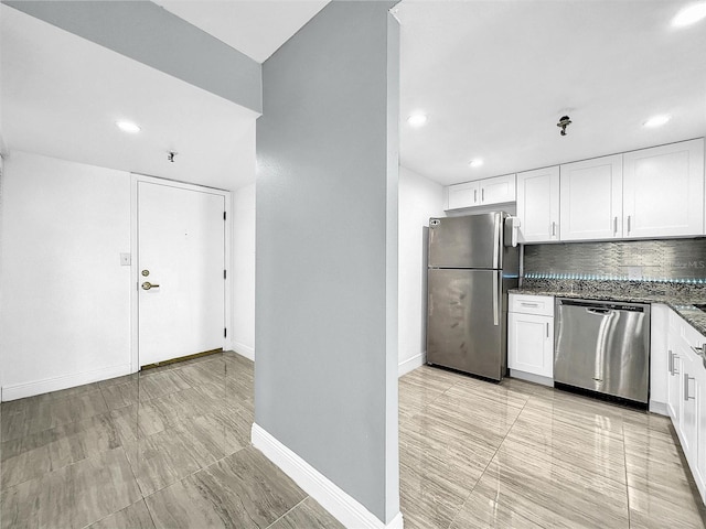 kitchen featuring tasteful backsplash, baseboards, dark stone countertops, appliances with stainless steel finishes, and white cabinetry