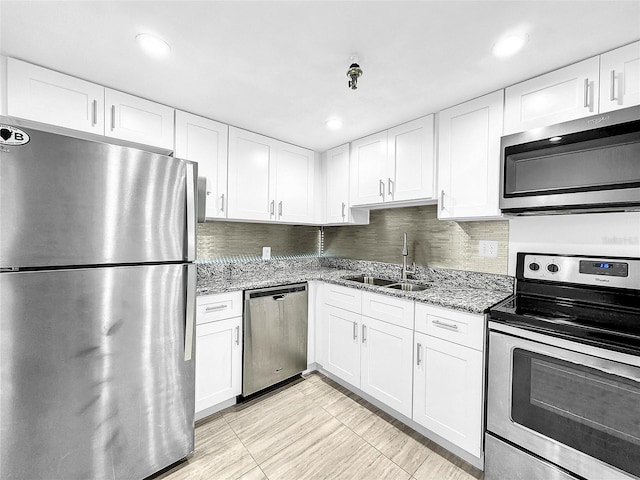 kitchen with light stone counters, white cabinets, stainless steel appliances, and a sink