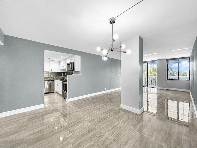 unfurnished living room featuring a chandelier and baseboards