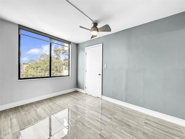 spare room featuring ceiling fan and baseboards