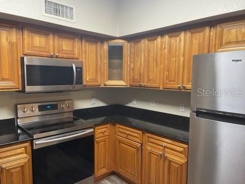 kitchen with stainless steel appliances and dark stone countertops