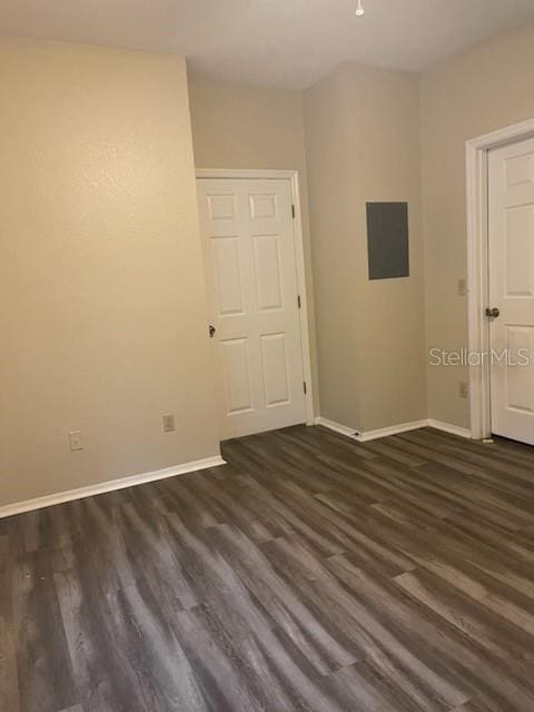 spare room featuring electric panel and dark wood-type flooring