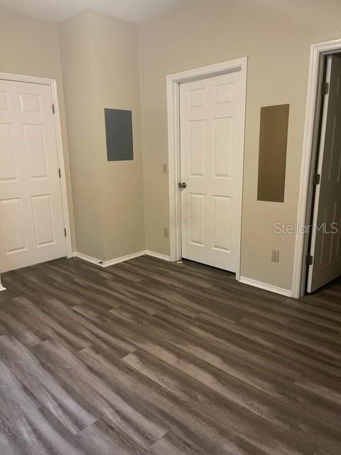 unfurnished bedroom with electric panel and dark hardwood / wood-style flooring