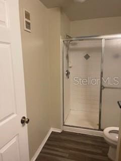 bathroom featuring hardwood / wood-style floors, toilet, and an enclosed shower