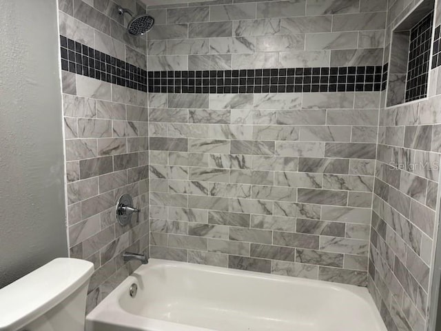 bathroom featuring toilet and tiled shower / bath combo