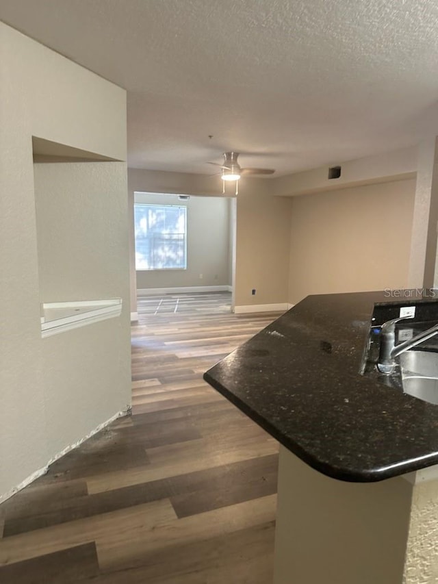 kitchen with a textured ceiling, sink, kitchen peninsula, and hardwood / wood-style floors