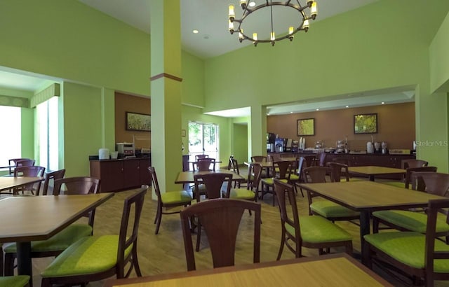 dining room with a high ceiling, an inviting chandelier, and light hardwood / wood-style floors