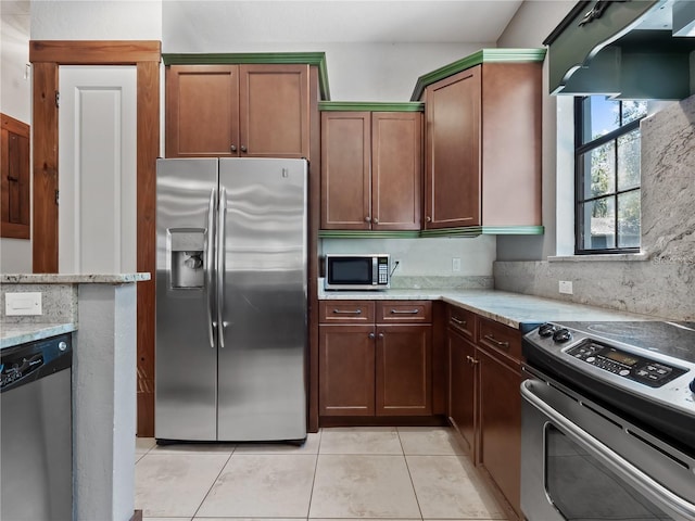 kitchen featuring backsplash, light stone counters, light tile patterned flooring, and appliances with stainless steel finishes