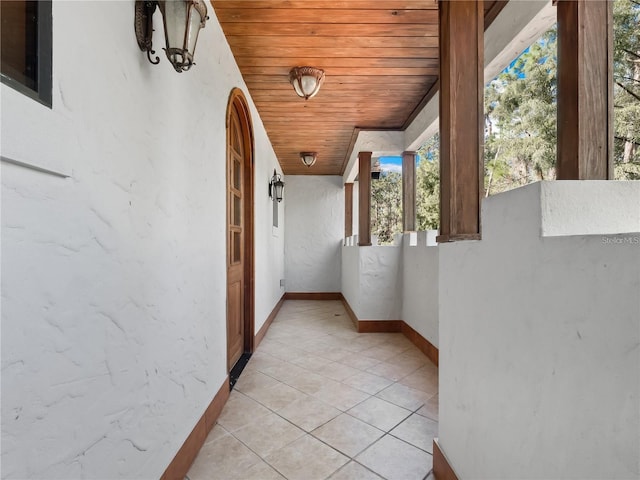 hall featuring light tile patterned floors and wooden ceiling