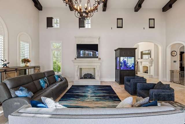 living room featuring light tile floors, a high ceiling, a chandelier, and beamed ceiling