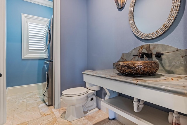 bathroom featuring sink, stacked washer and dryer, tile floors, and toilet