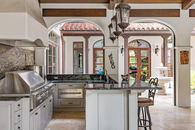 kitchen with beamed ceiling, backsplash, a healthy amount of sunlight, and sink