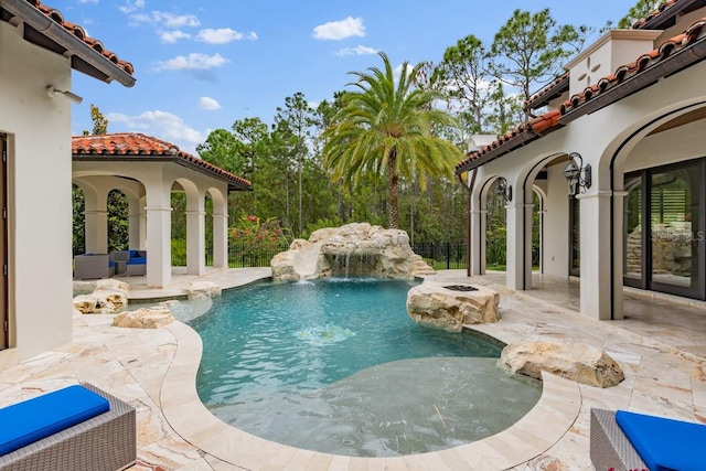 view of swimming pool with pool water feature and a patio area