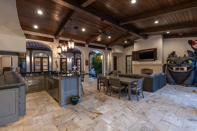 kitchen featuring a fireplace, wood ceiling, ceiling fan with notable chandelier, and pendant lighting