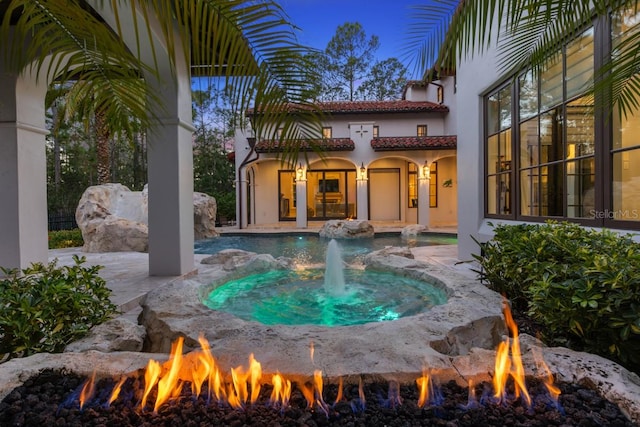 exterior space featuring a patio, a fire pit, and pool water feature