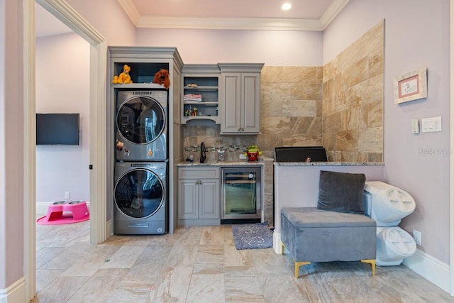 washroom featuring stacked washer / dryer, sink, light tile floors, beverage cooler, and ornamental molding