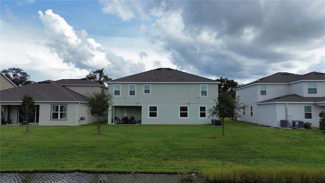 back of house with central AC unit and a yard