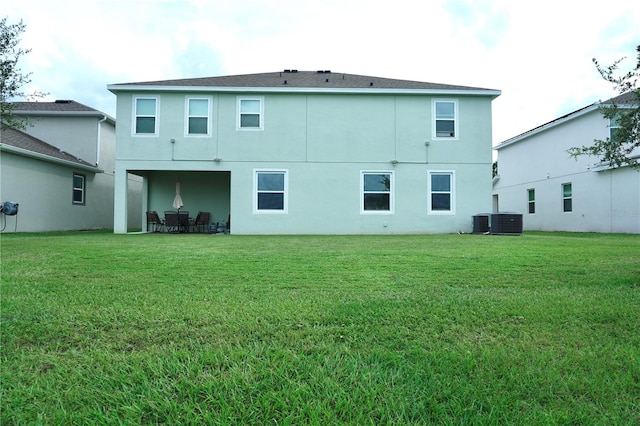 rear view of house with central AC and a yard