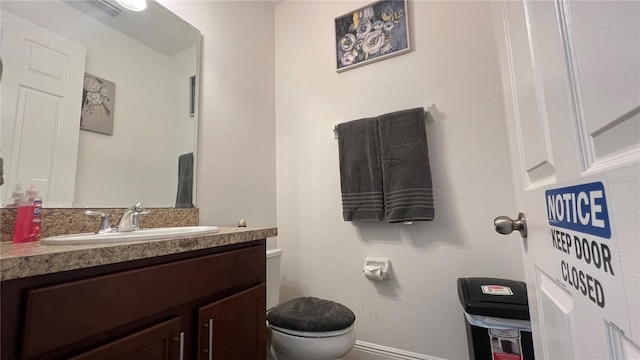 bathroom featuring vanity with extensive cabinet space and toilet