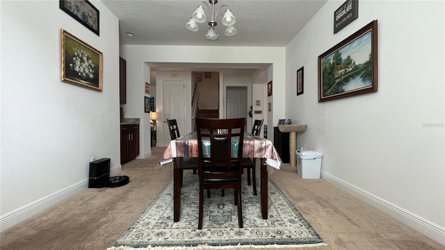 dining area featuring a textured ceiling, light colored carpet, and a notable chandelier