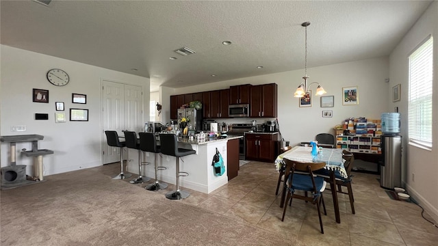 kitchen with hanging light fixtures, a kitchen breakfast bar, stainless steel appliances, a center island with sink, and a chandelier