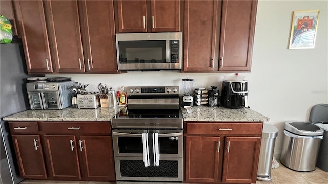 kitchen featuring light tile floors, stainless steel appliances, and light stone countertops