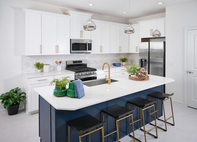 kitchen featuring backsplash, stainless steel appliances, a center island with sink, white cabinets, and pendant lighting