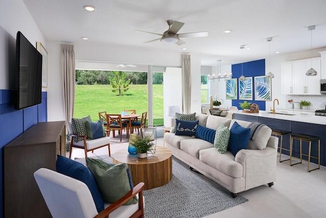 living room featuring light tile floors, sink, and ceiling fan with notable chandelier