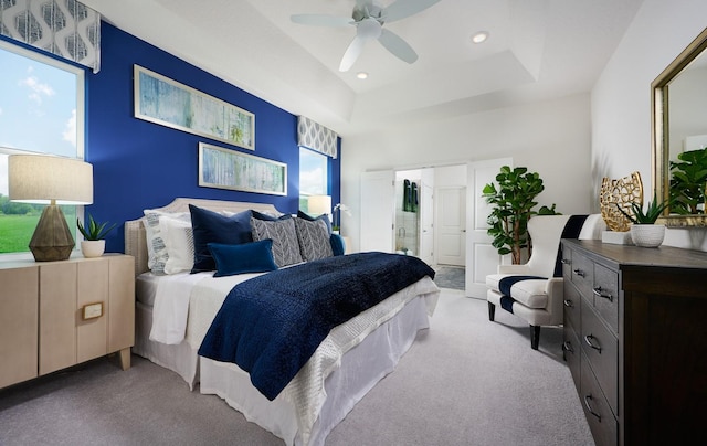 bedroom featuring carpet floors, a tray ceiling, ceiling fan, and multiple windows