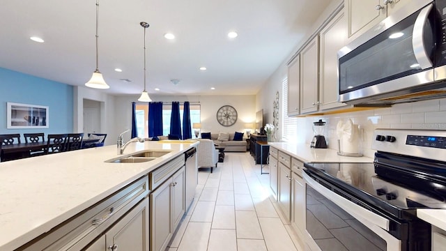 kitchen featuring stainless steel appliances, light tile flooring, tasteful backsplash, hanging light fixtures, and sink