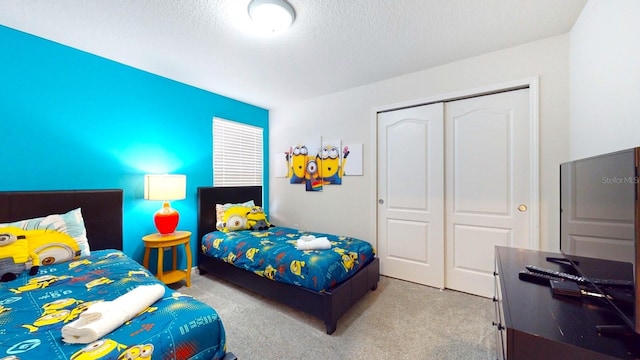 bedroom featuring light colored carpet, a closet, and a textured ceiling