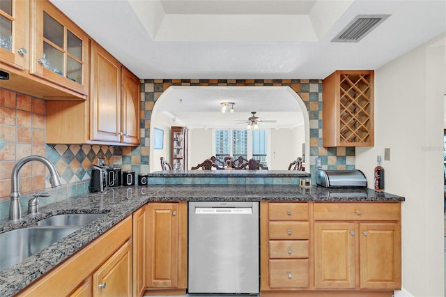 kitchen with dark stone countertops, tasteful backsplash, ceiling fan, and stainless steel dishwasher