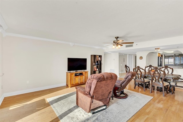 living room with light hardwood / wood-style floors, ceiling fan, and crown molding