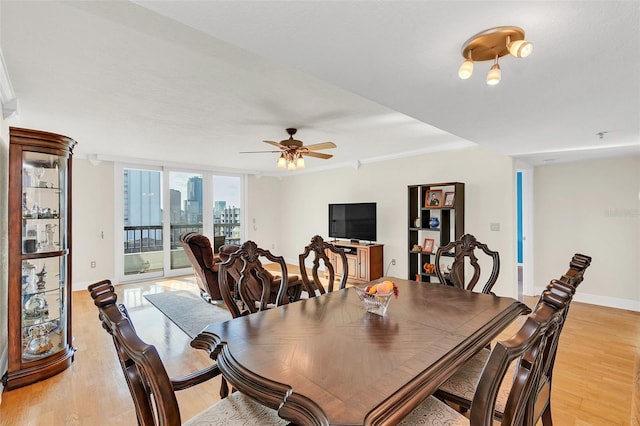 dining area with light hardwood / wood-style floors, ceiling fan, and a wall of windows