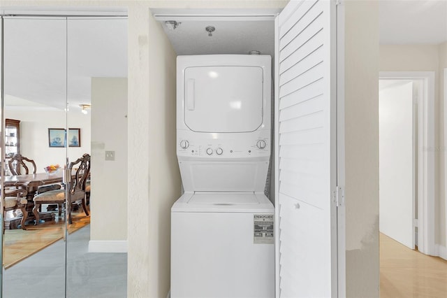 laundry area with stacked washer / dryer and light wood-type flooring