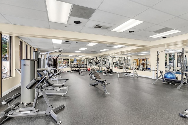 gym with a drop ceiling and a wealth of natural light