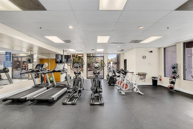 gym with floor to ceiling windows and a drop ceiling