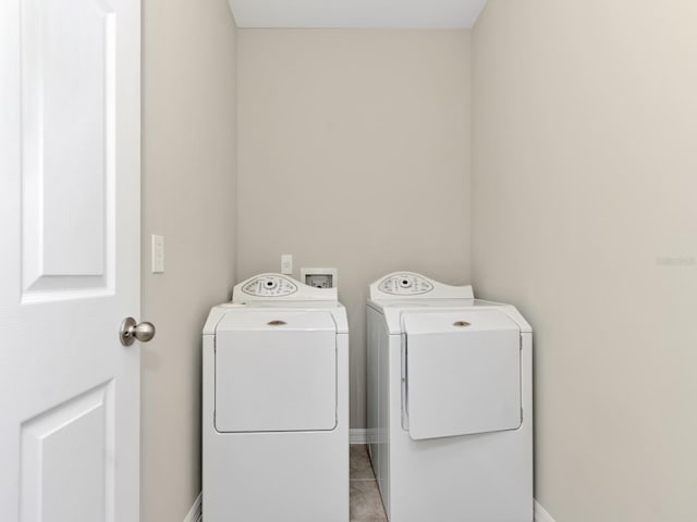 clothes washing area featuring light tile flooring, washer hookup, and washing machine and clothes dryer