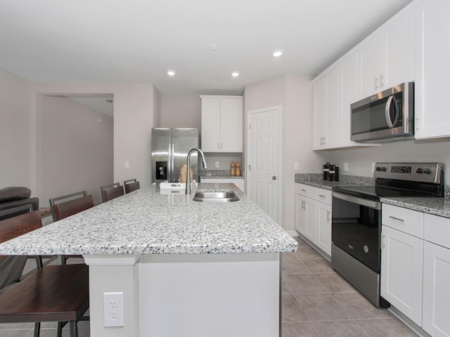 kitchen featuring light tile flooring, stainless steel appliances, a breakfast bar area, an island with sink, and sink