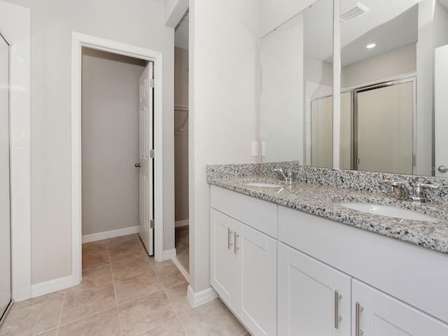 bathroom featuring dual vanity, an enclosed shower, and tile flooring