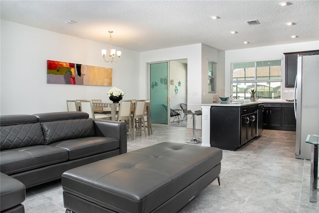 tiled living room featuring a textured ceiling, a notable chandelier, and sink