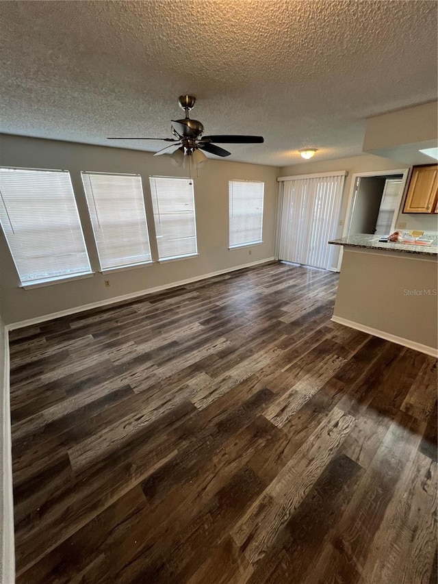 unfurnished living room with dark hardwood / wood-style floors, a textured ceiling, and ceiling fan