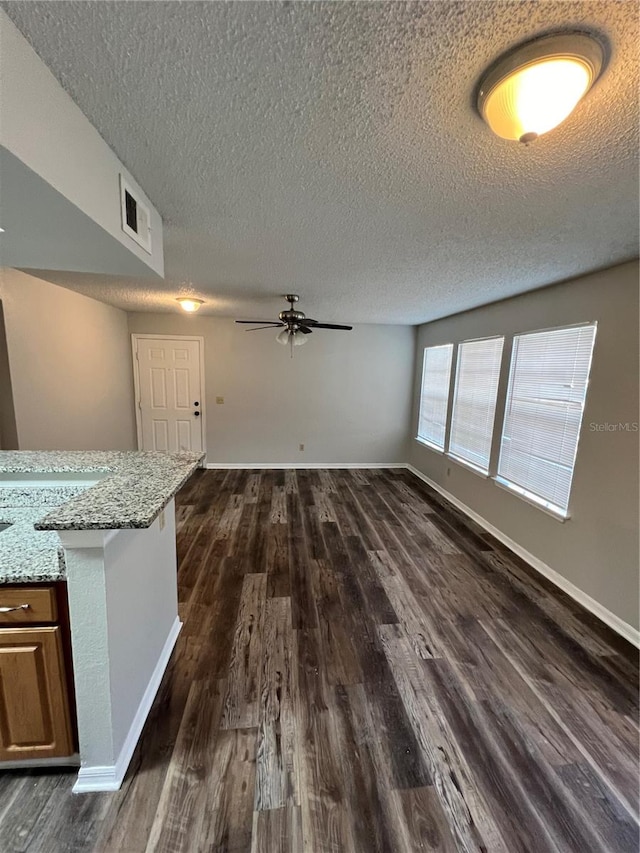 spare room featuring a textured ceiling, ceiling fan, and dark wood-type flooring