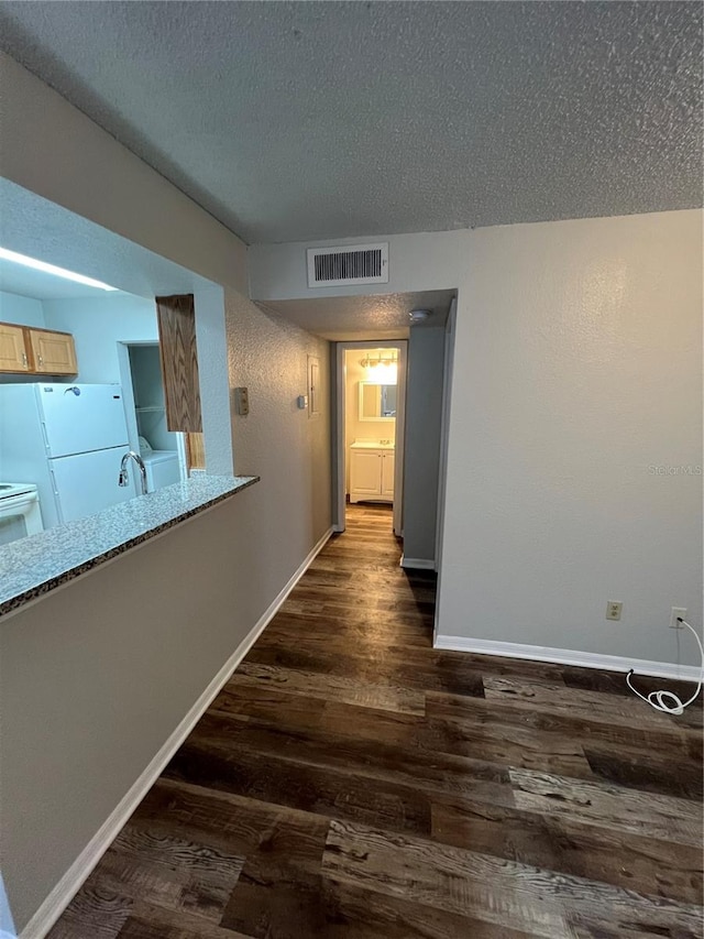 hallway with dark wood-type flooring and a textured ceiling