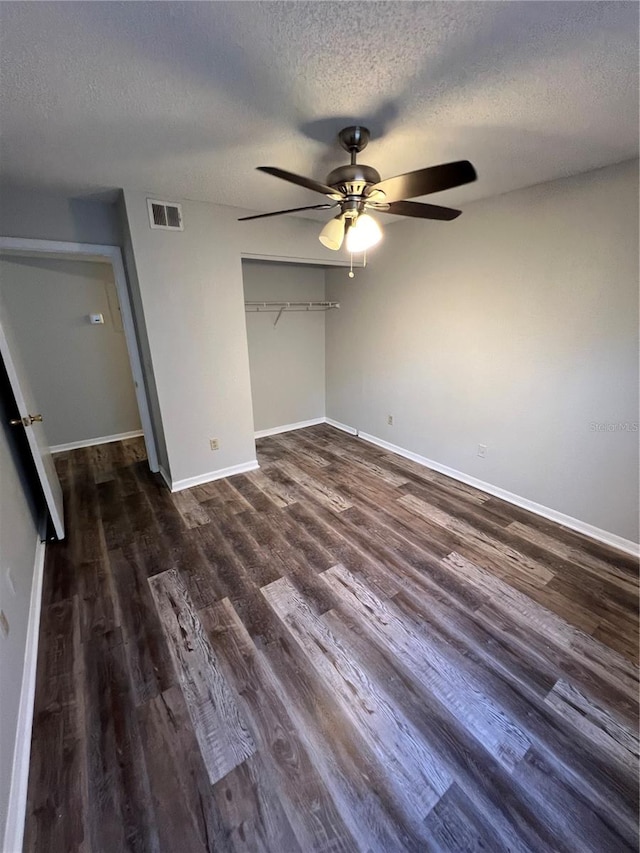 unfurnished bedroom with a textured ceiling, dark hardwood / wood-style flooring, a closet, and ceiling fan