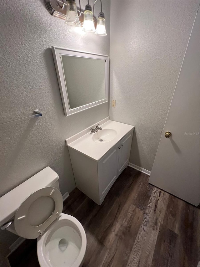 bathroom with toilet, hardwood / wood-style floors, and vanity