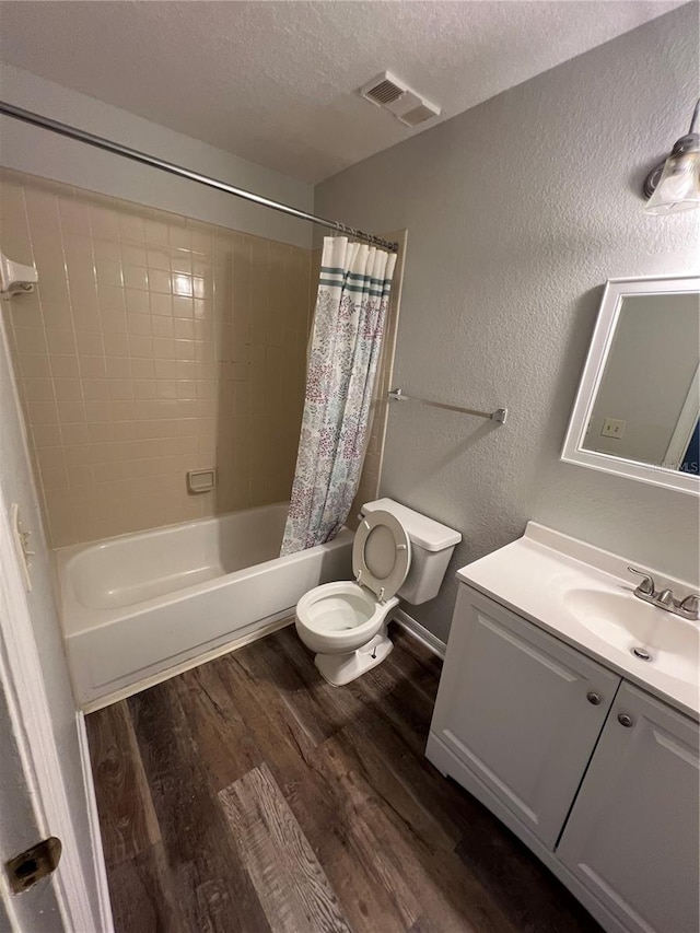 full bathroom with vanity, hardwood / wood-style floors, a textured ceiling, toilet, and shower / bath combination with curtain